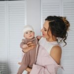 A loving mother holds her baby indoors, showcasing warmth and affection.